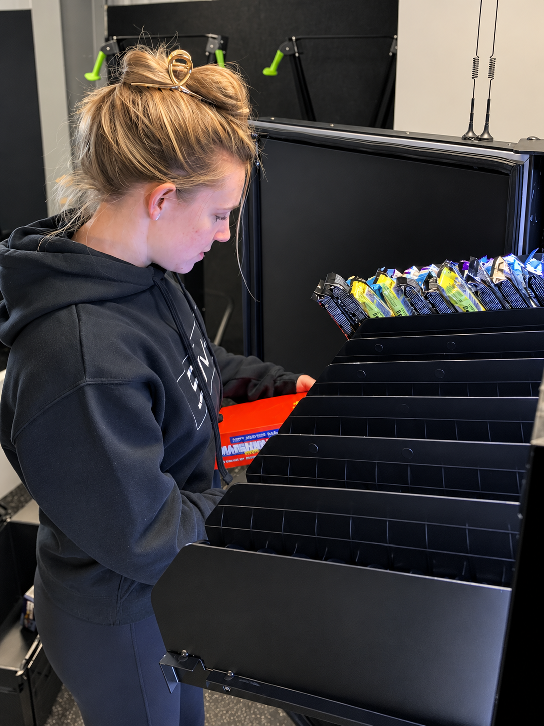Team member loading nutrition bars into a vending machine shelf.